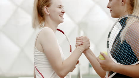 Caucasian-female-tennis-players-handshaking-at-the-tennis-court-after-match-or-practice.-4K-UHD-RAW-graded-footage